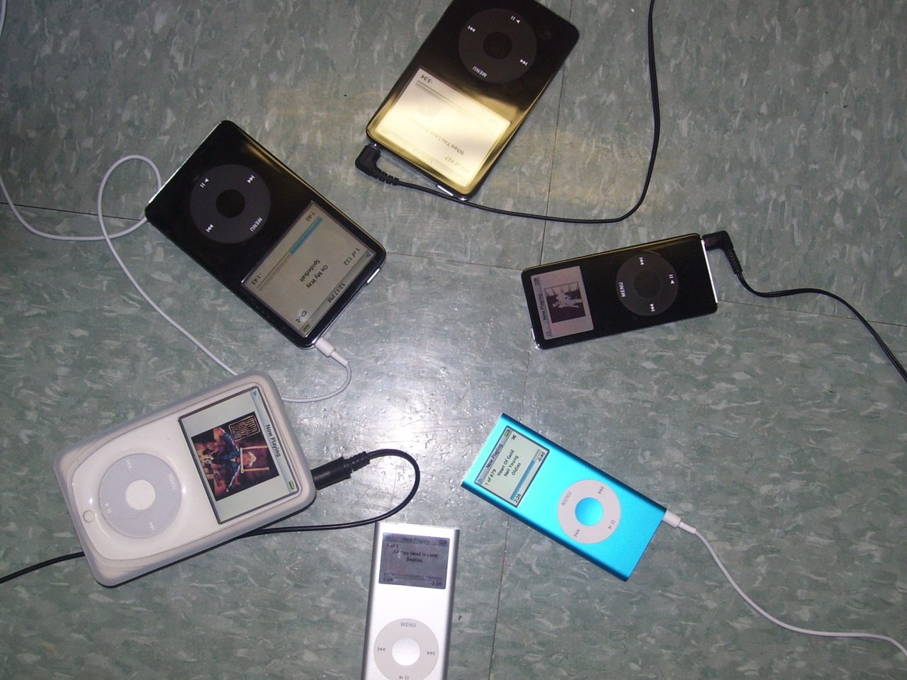 Imagem de seis iPods de dois modelos diferentes, organizados de forma circular