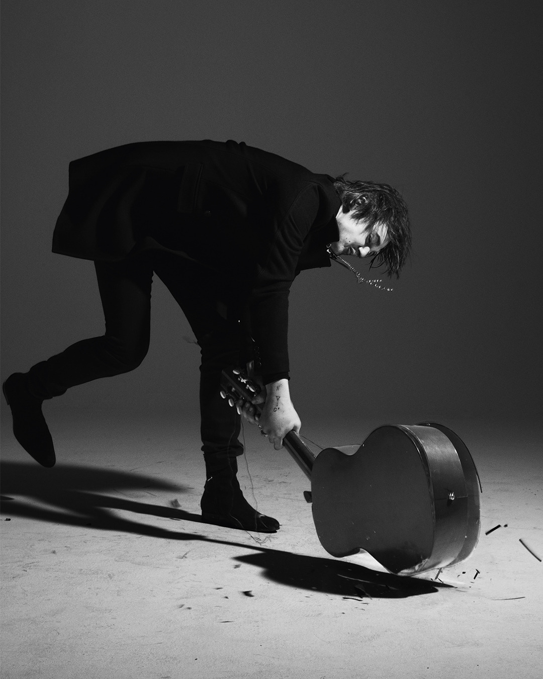 Pete Doherty totalmente vestido de preto, quebrando um violão no chão ao melhor estilo rock&rsquo;n&rsquo;roll