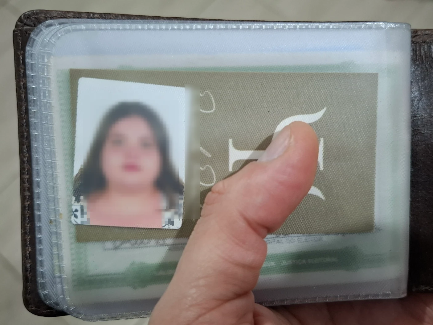 Uma foto de uma carteira aberta, dentro do compartimento transparente tem uma foto de uma mulher.