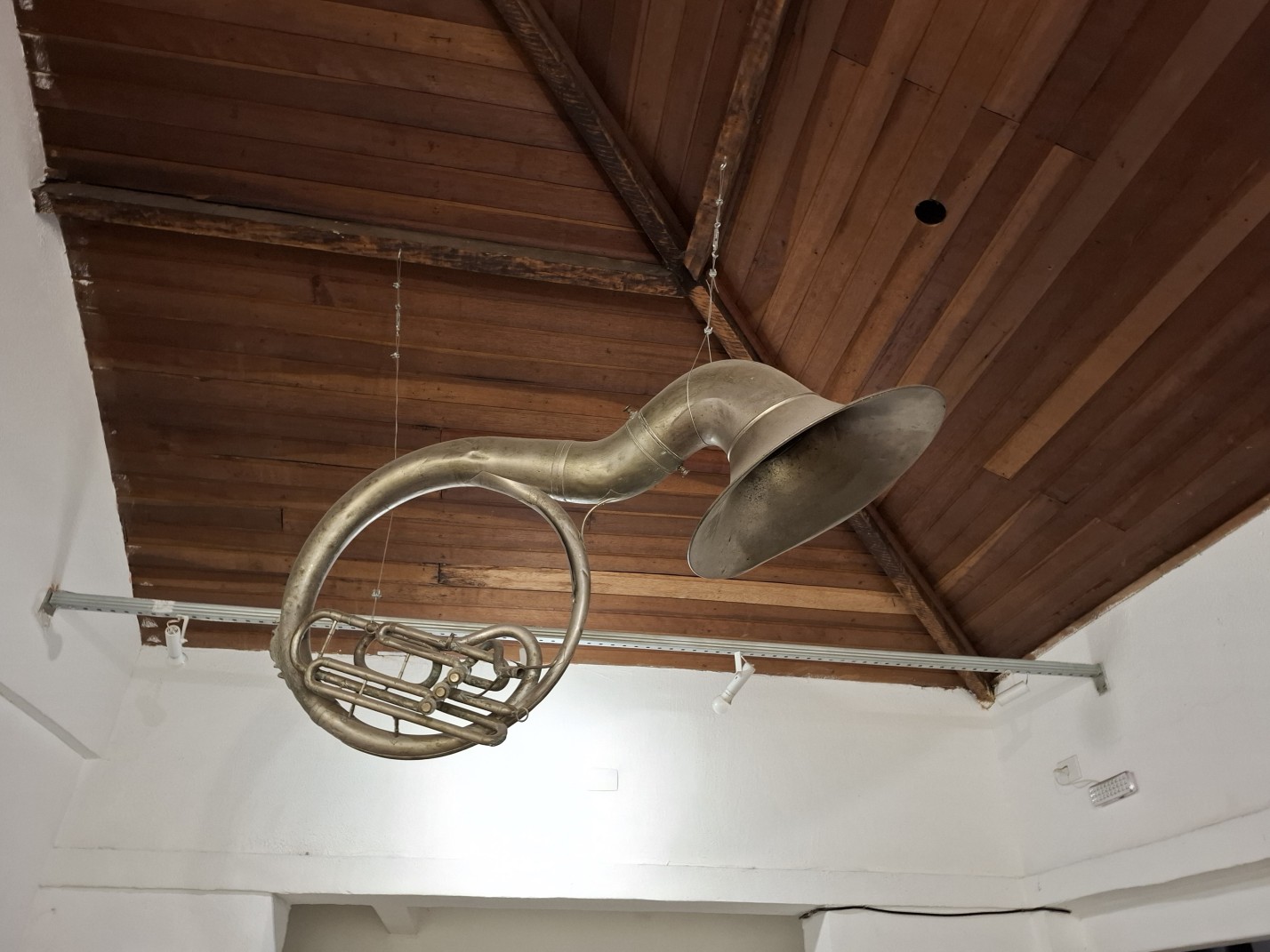 Um Sousafone (instrumento de sopro grande) usado como decoração, pendurado no teto, dentro do local.