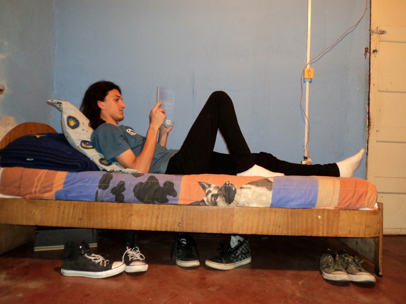 Eu deitando numa cama de solteiro lendo um livro