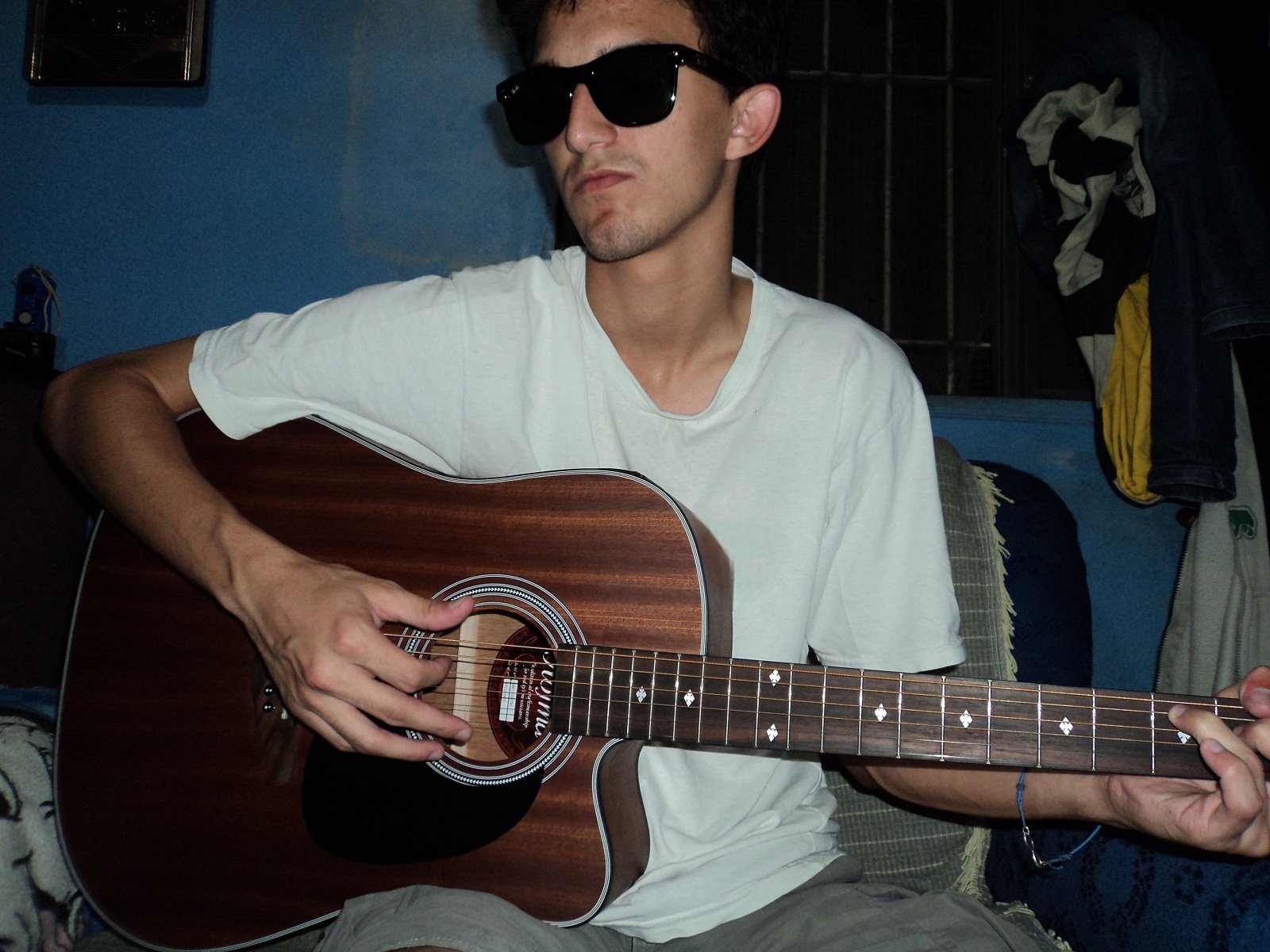 Eu tocando violão usando um ôculos escuro