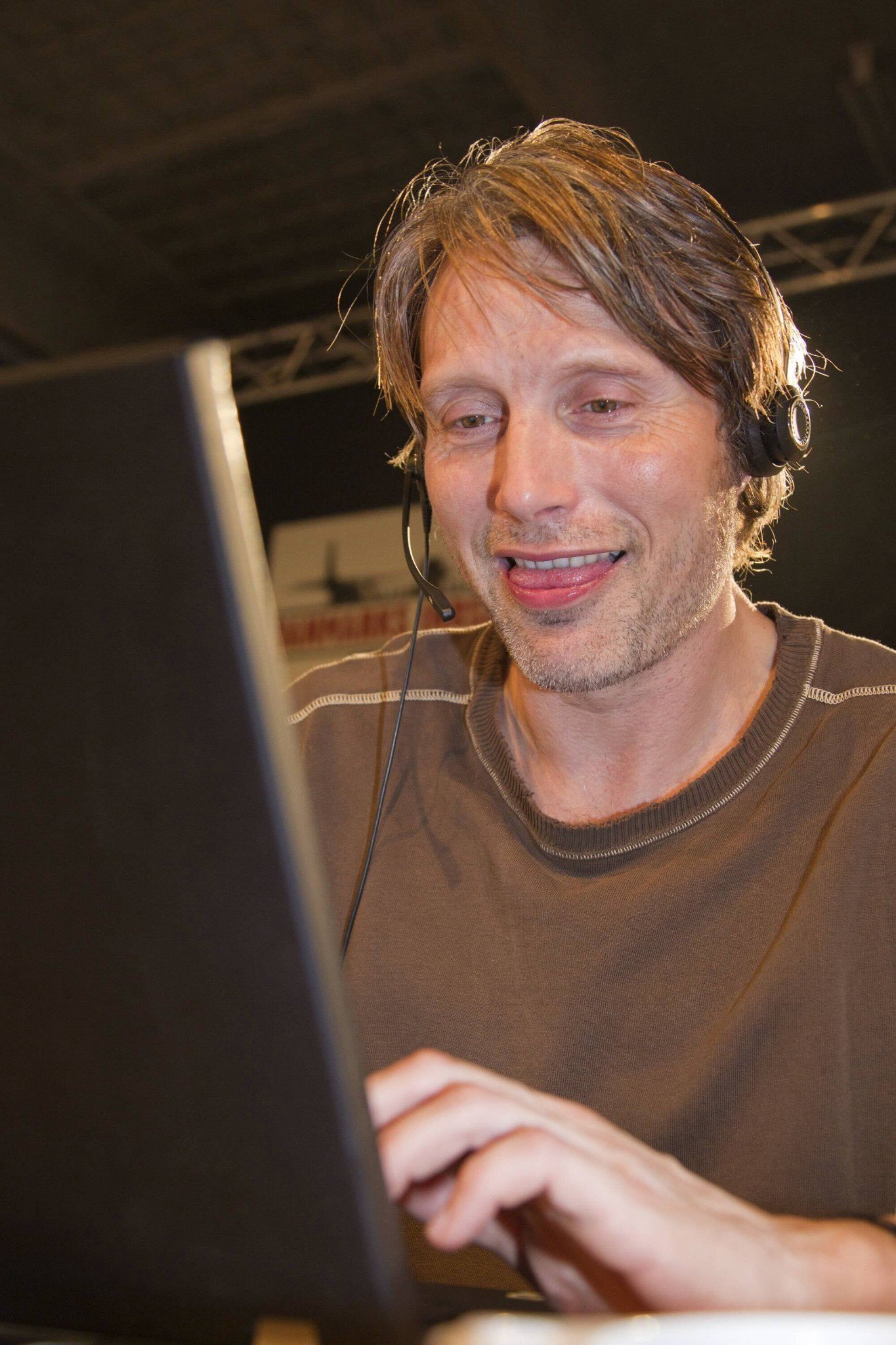Ator Mads Mikkelsen usando o computador dando risada